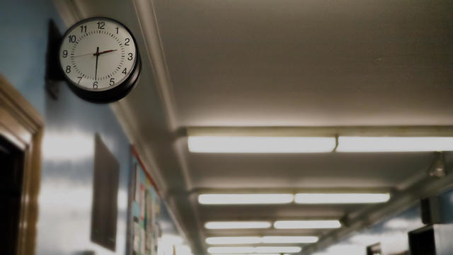 partial darkened view of school corridor with defocused exit sign in the background 