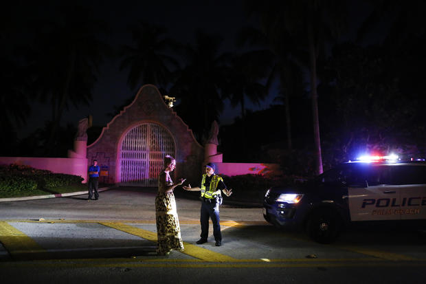 A woman talks to Palm Beach police officer in front of former President Donald Trump's house at Mar-A-Lago on Aug. 8, 2022, in Palm Beach, Florida. 