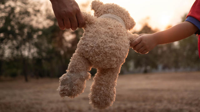 Close-up Hand of Asian mother and her daughter holding teddy bear's  hands and walking together. Mother and child with love and relationship concept. 