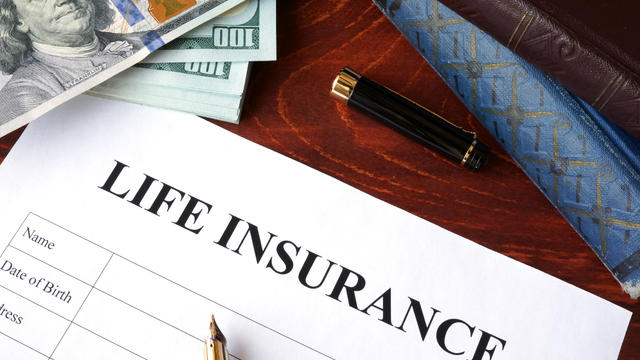 Life insurance policy and currency on a table. 