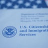 Hand touching Letter (Envelope) from USCIS on  flag of USA background. 