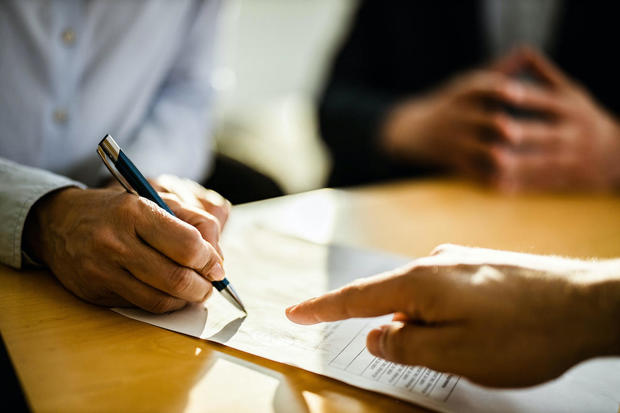Close-up of an unrecognizable person signing a contract. 