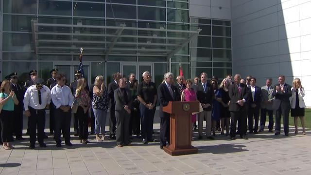 Dozens of Nassau County officials stand together behind a podium. 