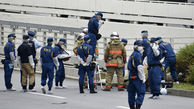 Police officers investigate at the site where a man who was protesting a state funeral for former Japanese Prime Minister Shinzo Abe set himself on fire 