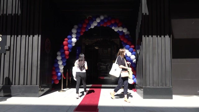 A red carpet and a balloon arch are placed outside the entrance to a St. Francis College building. 