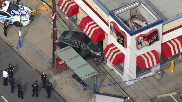 An aerial shot of a vehicle crashed into the window of a combination KFC/Pizza Hut. 