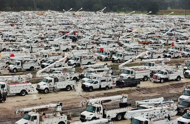 Utility trucks are staged in a rural lot in preparation for Hurricane Ian