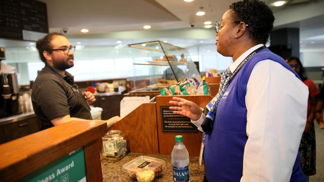 Peet's Coffee and Tea employee Dugaldo Avalos (left) converses with Annette Leonard, a baggage agent with ABM, as she purchases a bottled water and meal in Terminal 3 at the San Francisco International Airport in San Francisco, Calif., on Thursday, August 