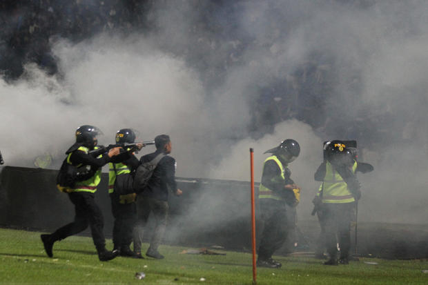 A riot police officer fires tear gas after the football match between Arema vs Persebaya at Kanjuruhan Stadium, Malang 
