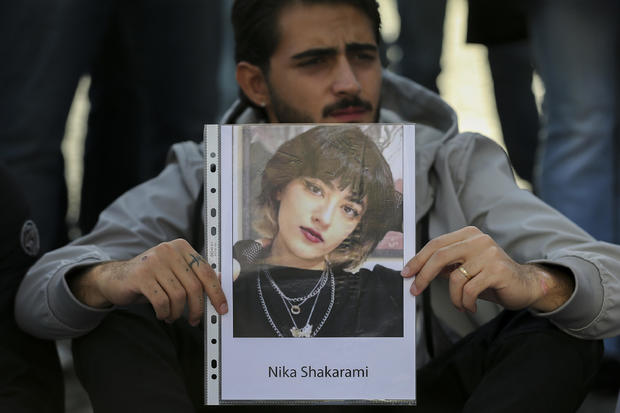 A man with a photograph of Iranian woman Nika Shakarami, 