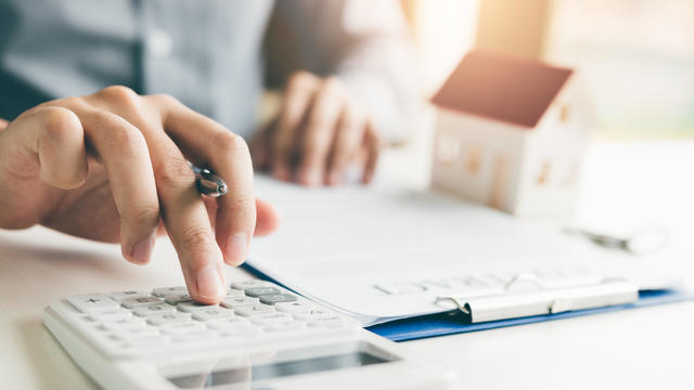 Home agents are using a calculator to calculate the loan period each month for the customer. 