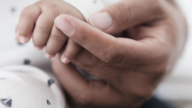 Close up of father holding hand of baby son 