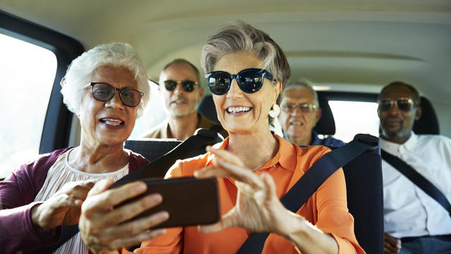 Smiling woman using smart phone by friend in car 