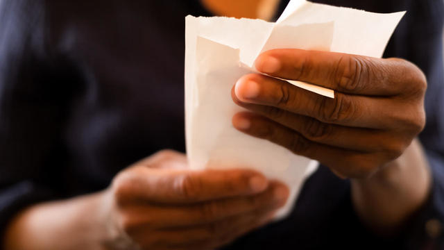 economy: black woman holding multiple retail receipts 