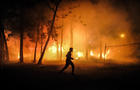 A man runs past a burning forest to help save homes during a 