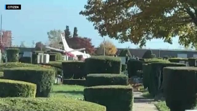 A small plane sits in a cemetery. 