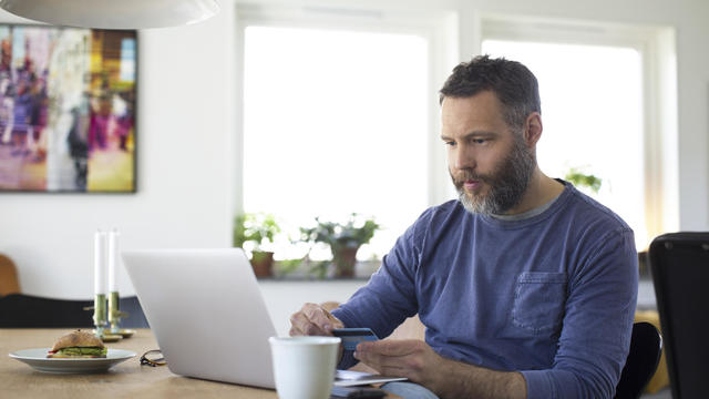 Businessman paying through credit card on laptop at home 