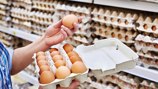 In hands of woman packing eggs in supermarket 