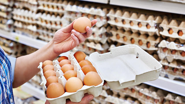 In hands of woman packing eggs in supermarket 