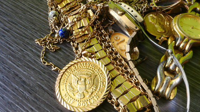 Half dollar and other gold jewellery over a wooden table, closeup shot 