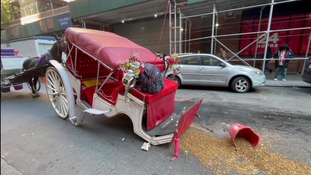 A horseless horse carriage hits in the street with a bucket of feed spilled. 