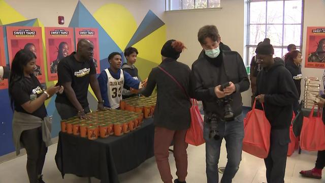 Volunteers hand out canned goods at a food giveaway. 