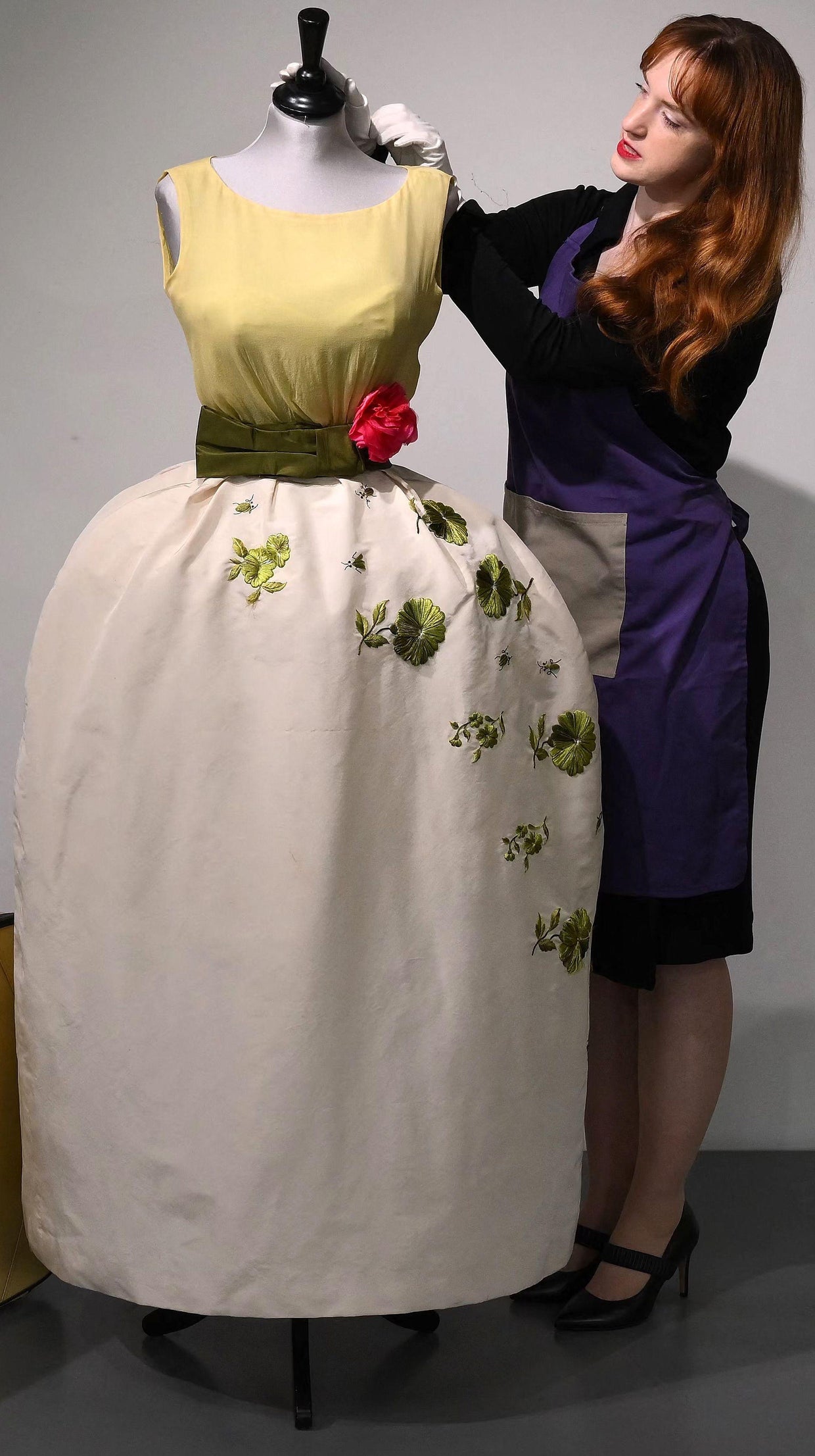 An employee poses with a Christian Dior dress worn by actor Elizabeth Taylor and recently discovered with other dresses in a suitcase, ahead of their sale at Kerry Taylor Auctions, in London on Nov. 25, 2022. 