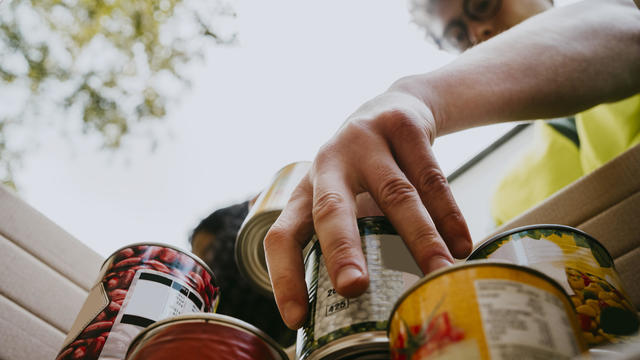 Young man holding canned food in box 