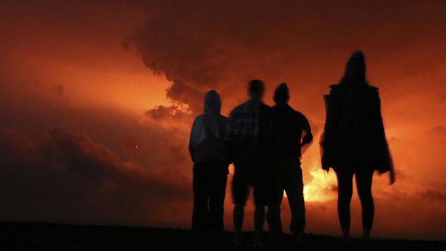 People watch the glow from lava erupting from Hawaii's Mauna Loa volcano Nov. 28, 2022, in Hilo, Hawaii. 