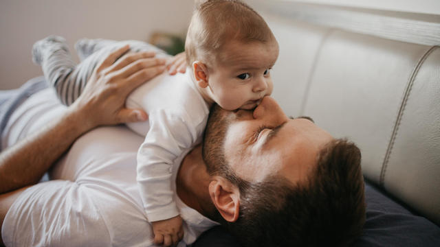 Father playing in bed with his little baby boy 