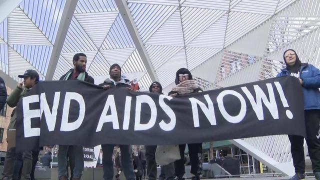 Several people hold a large banner that reads "END AIDS NOW!" 