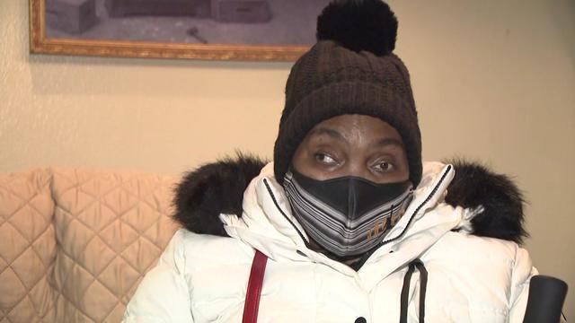 A woman wears a winter coat and hat inside her home, which she says has no heat. 