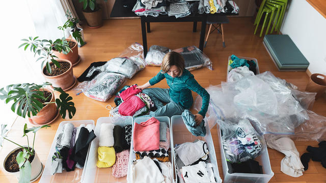 Woman organizes clothes in living room of her home 