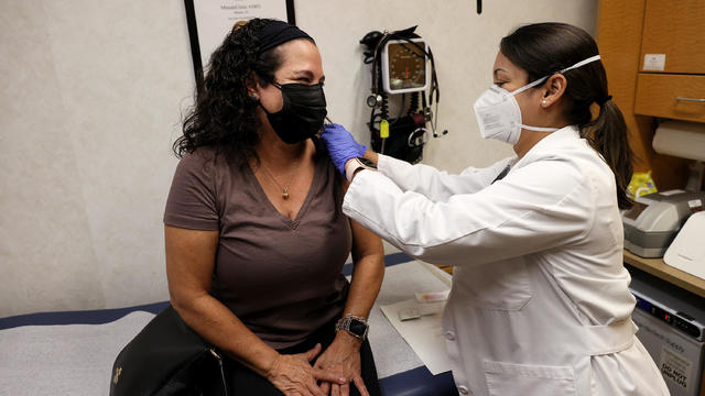 A nurse practitioner prepares to administer a flu shot to a woman in a Florida clinic 