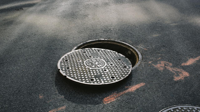 A manhole cover partially removed, close-up 