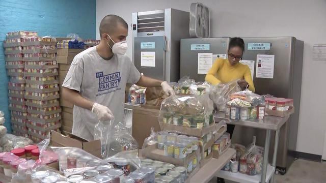 Two volunteers put food in bags in the kitchen of a New York Common Pantry location. 