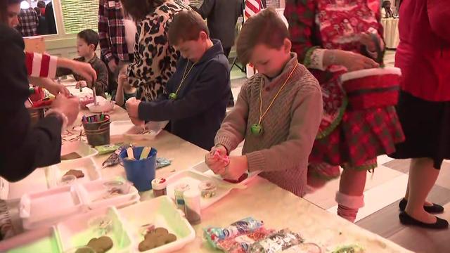 Children at a holiday party put icing on gingerbread cookies. 