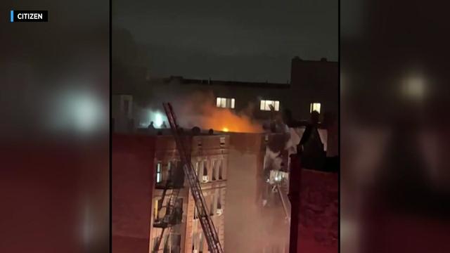 Flames can be seen on the roof of an apartment building. 