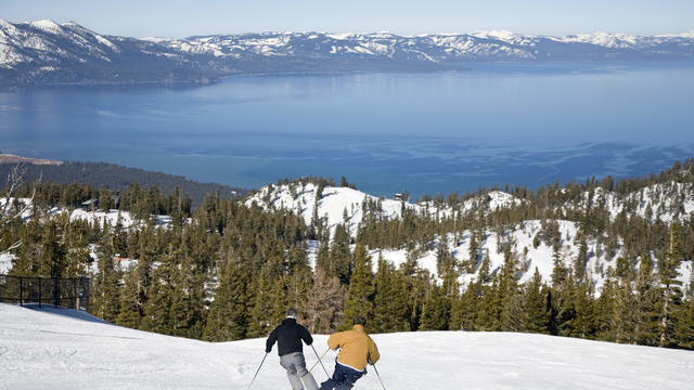 USA, California, Lake Tahoe, two men downhill skiing, rear view 