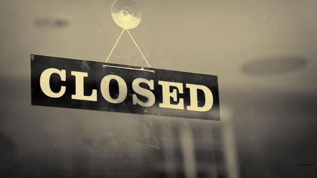 Black and white closeup of a Closed sign hanging on a window 