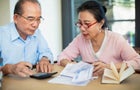 Senior couple working with bills at table 