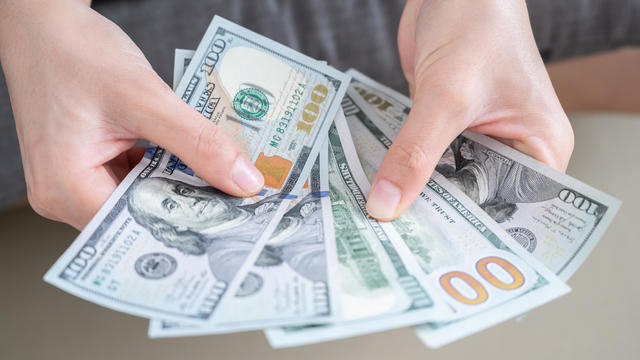 Close up of someone hands holding and counting American dollar banknotes in her hand. 