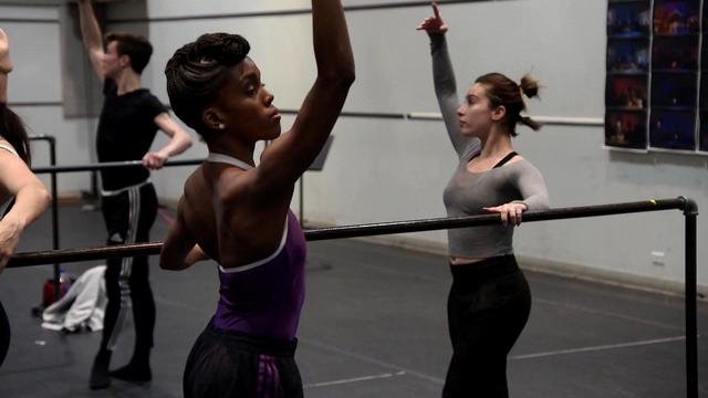 Broadway dancer Paige Fraser stands at a barre with other dancers. 