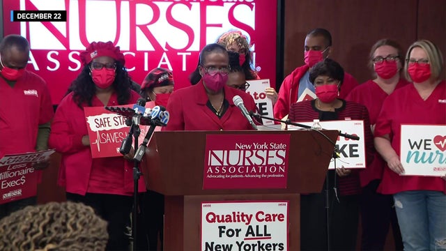 Members of the New York State Nurses Association stand behind a podium. 