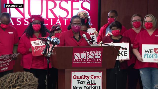 Members of the New York State Nurses Association stand behind a podium. 