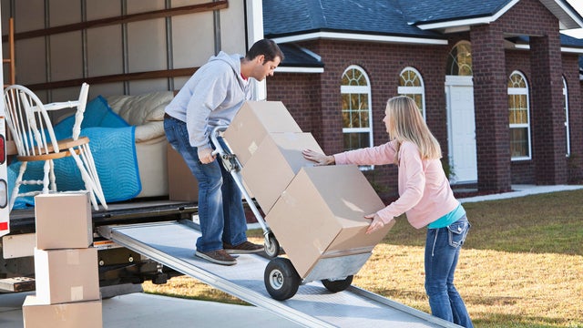 Couple unloading boxes from moving van 