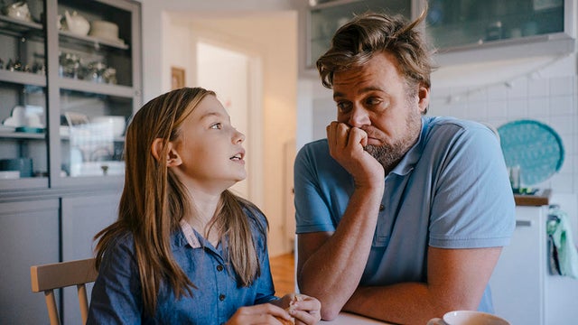 Daughter talking to father in kitchen at home 