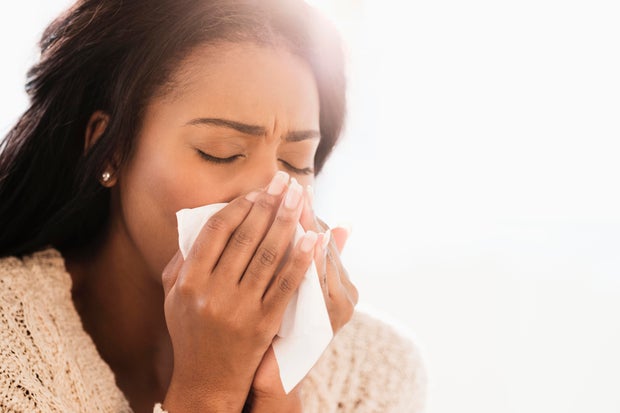 Mixed race woman blowing her nose 
