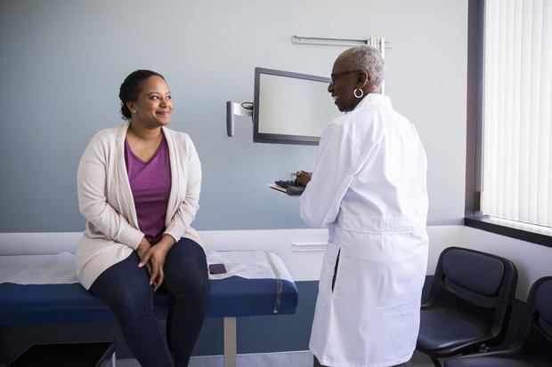 Smiling senior doctor talking to female patient in hospital 