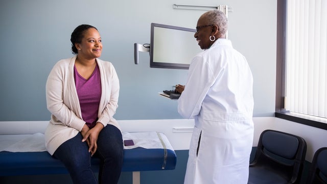 Smiling senior doctor talking to female patient in hospital 